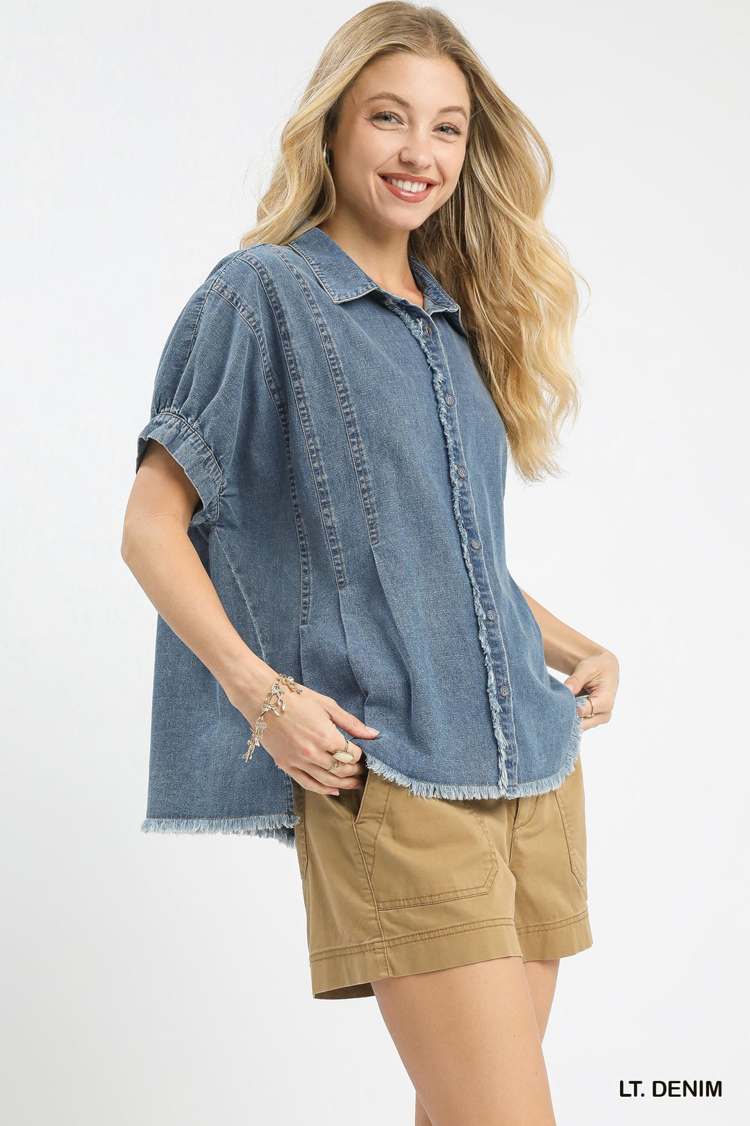 Woman wearing a light denim shirt and beige shorts on a white background