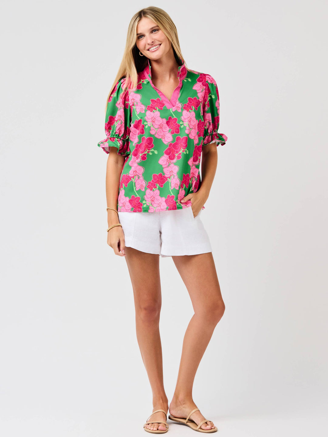 Woman wearing a colorful floral blouse and white shorts on a white background