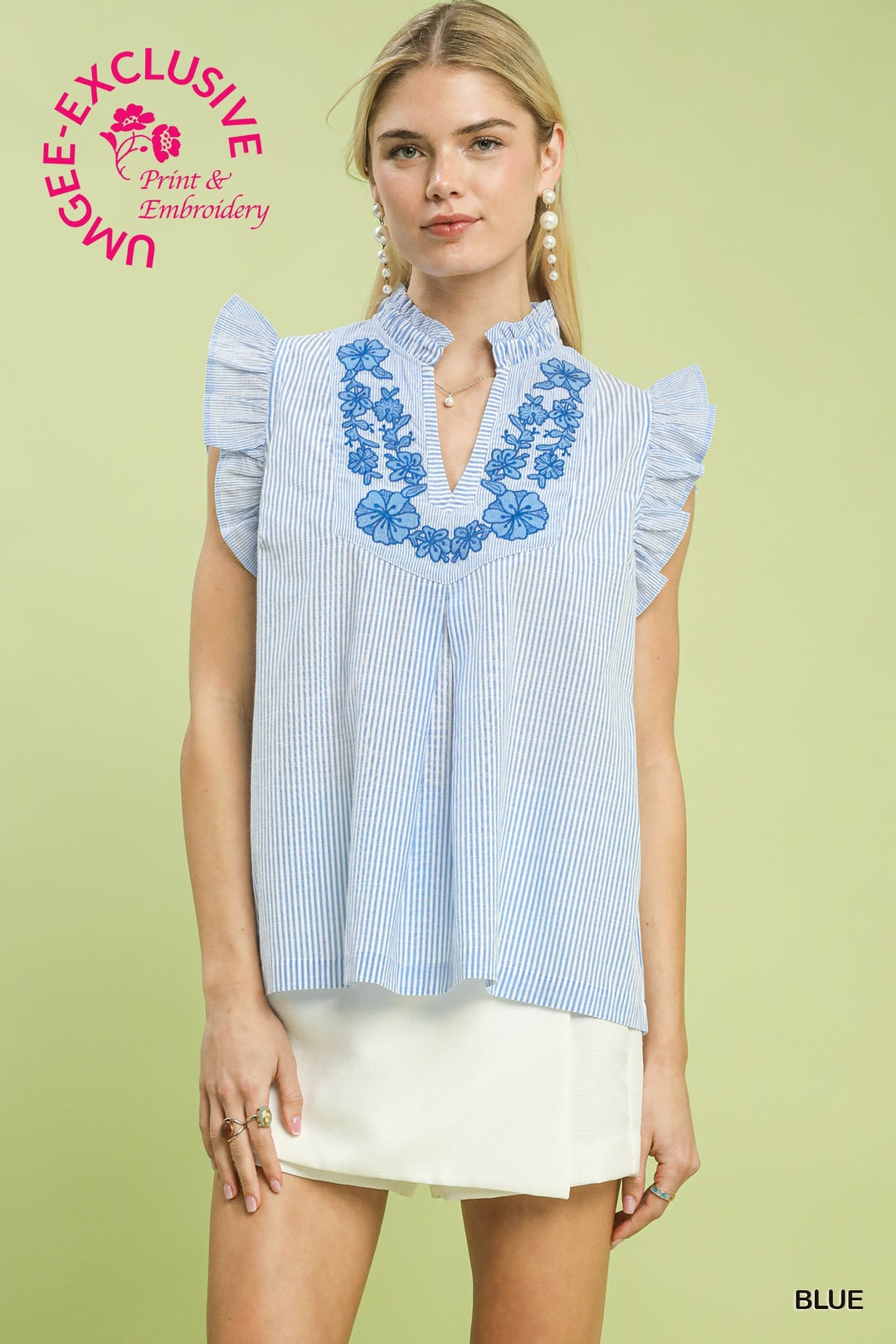 Woman wearing a blue and white striped blouse with floral embroidery on a light green background
