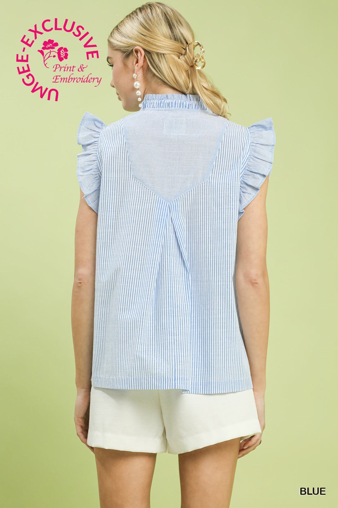 Woman wearing a blue and white striped shirt with ruffled sleeves on a light green background.