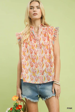 Woman wearing a sleeveless floral top and denim shorts against a light green background