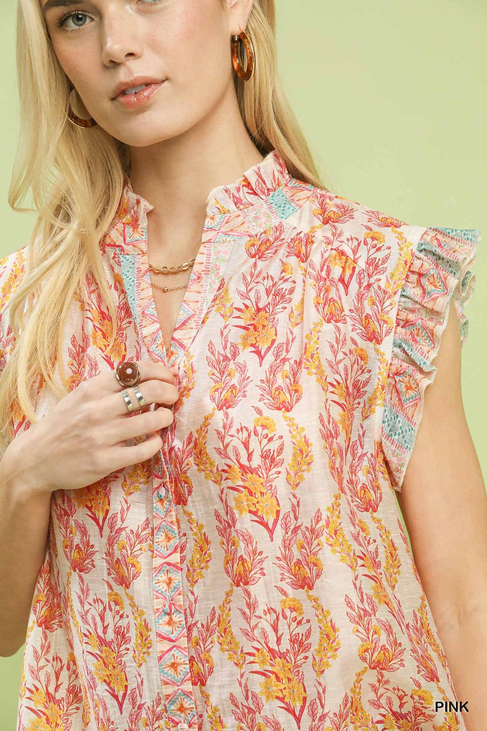 Woman wearing a colorful floral blouse against a light green background