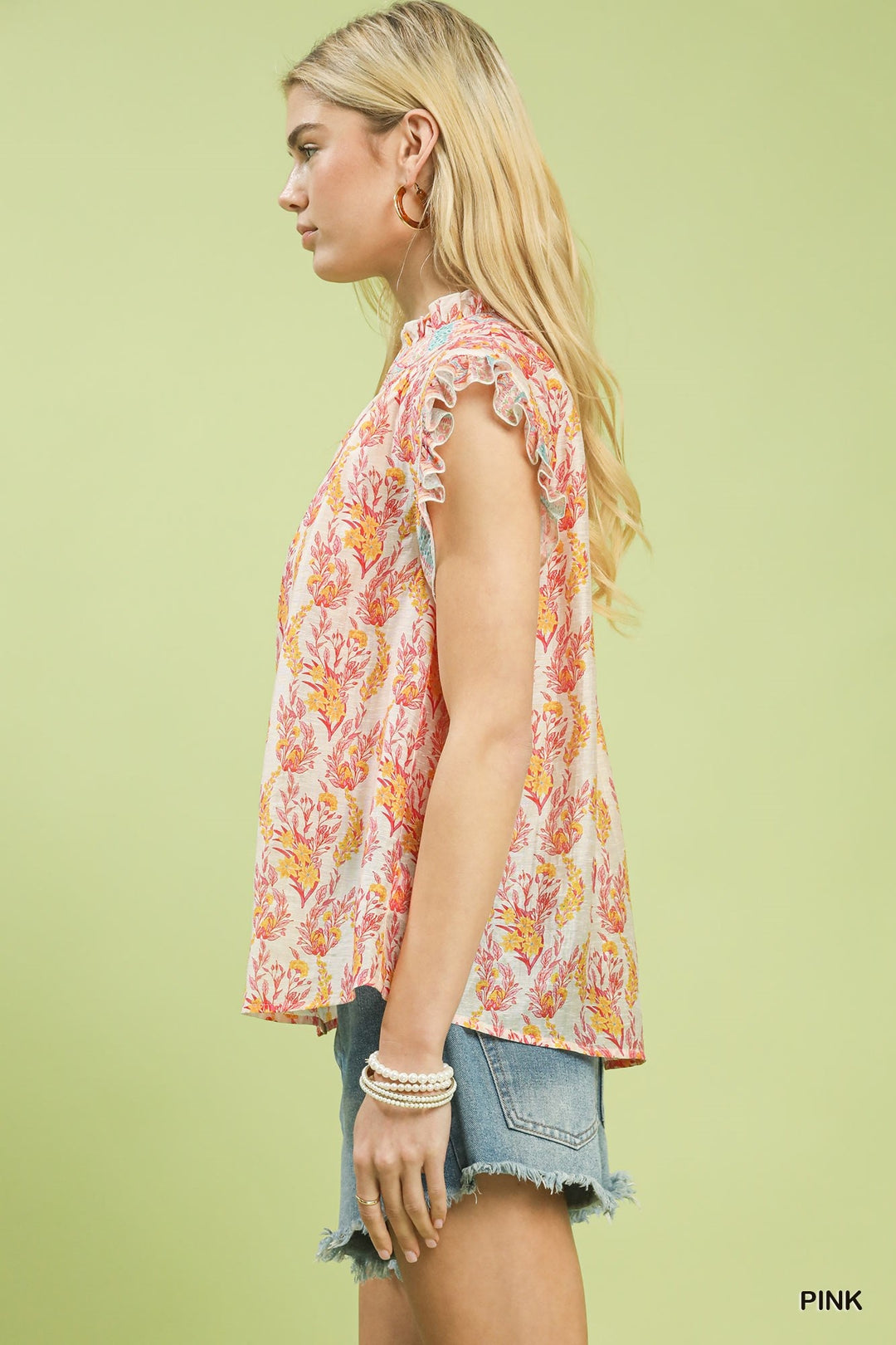 Woman wearing a floral sleeveless top against a light green background