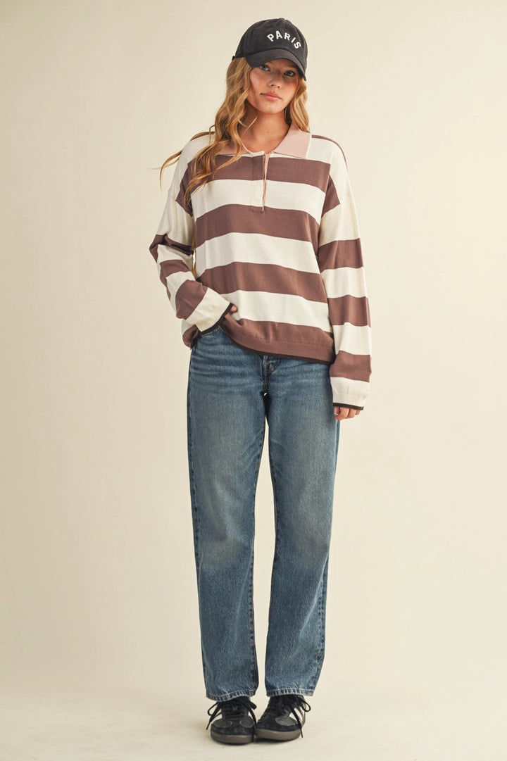 Woman wearing a striped sweater and cap against a plain background.
