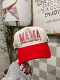 Red and beige cap with 'MAMA' text held by a person with colorful nails.