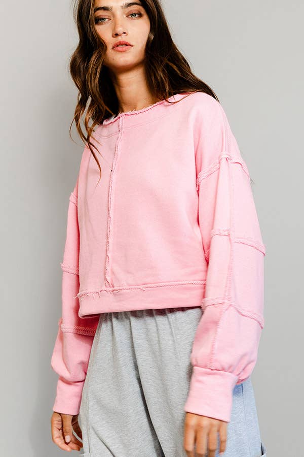 Person wearing a pink sweatshirt and gray pants on a plain background