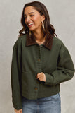 Woman wearing a green jacket with a brown collar against a plain background