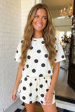Woman wearing a polka dot romper standing indoors.