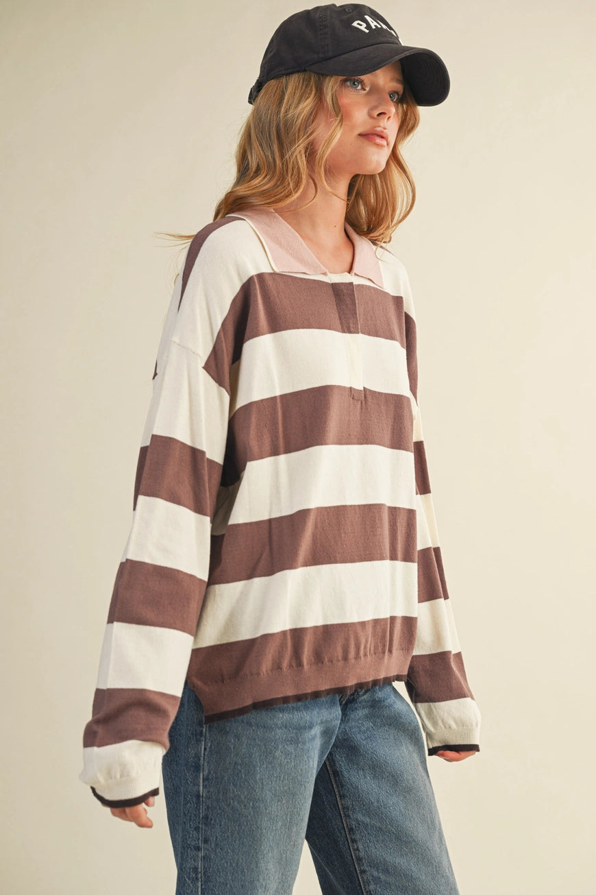 Woman wearing a striped sweater and cap against a plain background.