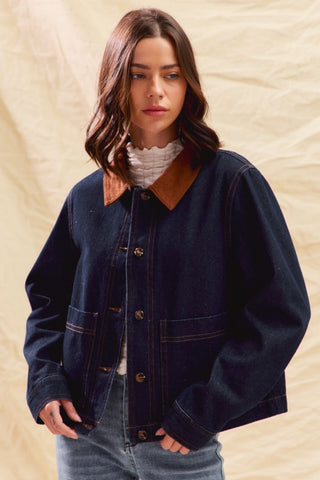 Woman wearing a dark blue jacket with a brown collar against a beige background
