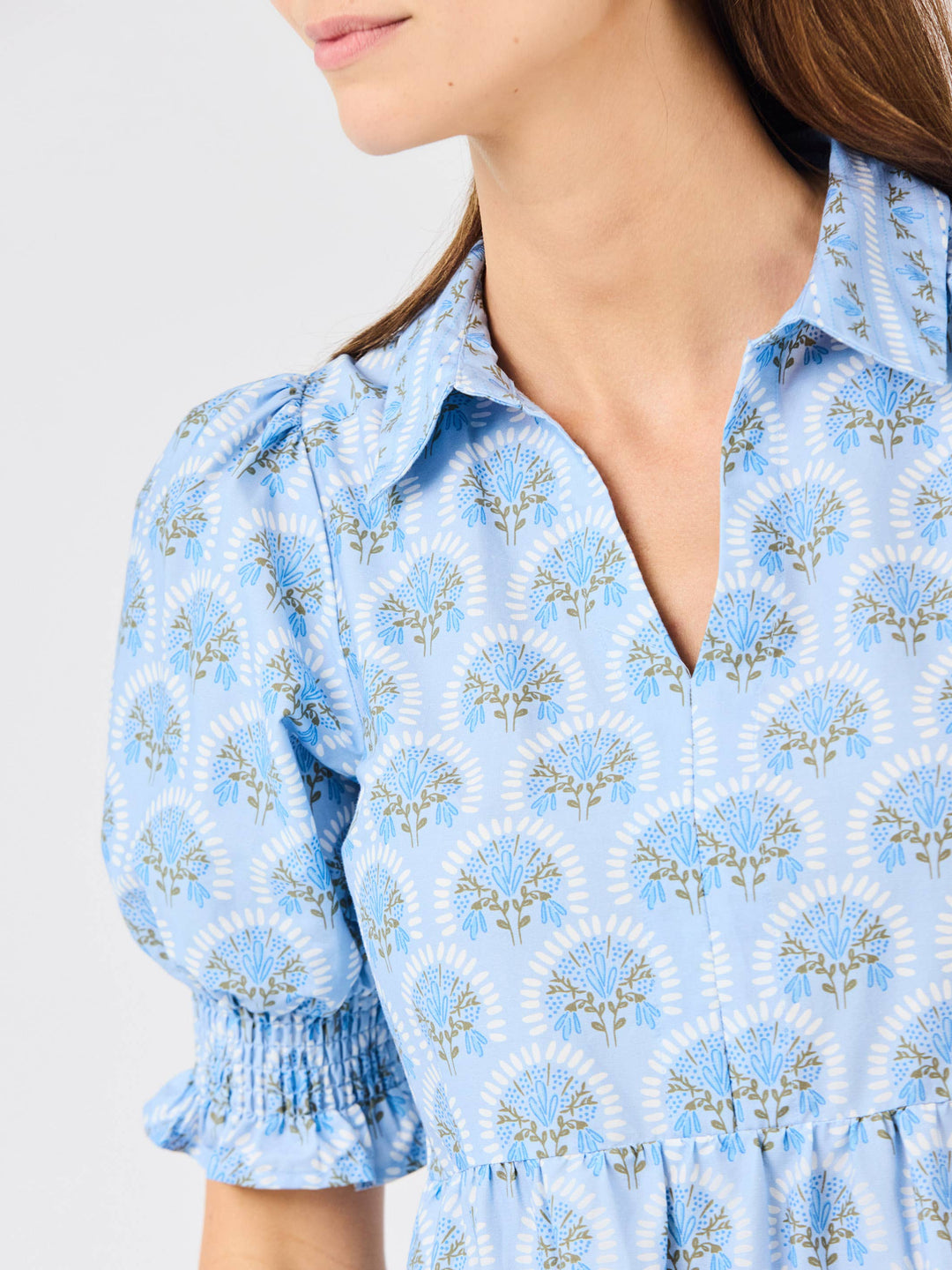 Close-up of a person wearing a blue floral dress with a plain background