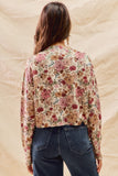 Person wearing a floral blouse and jeans against a beige background
