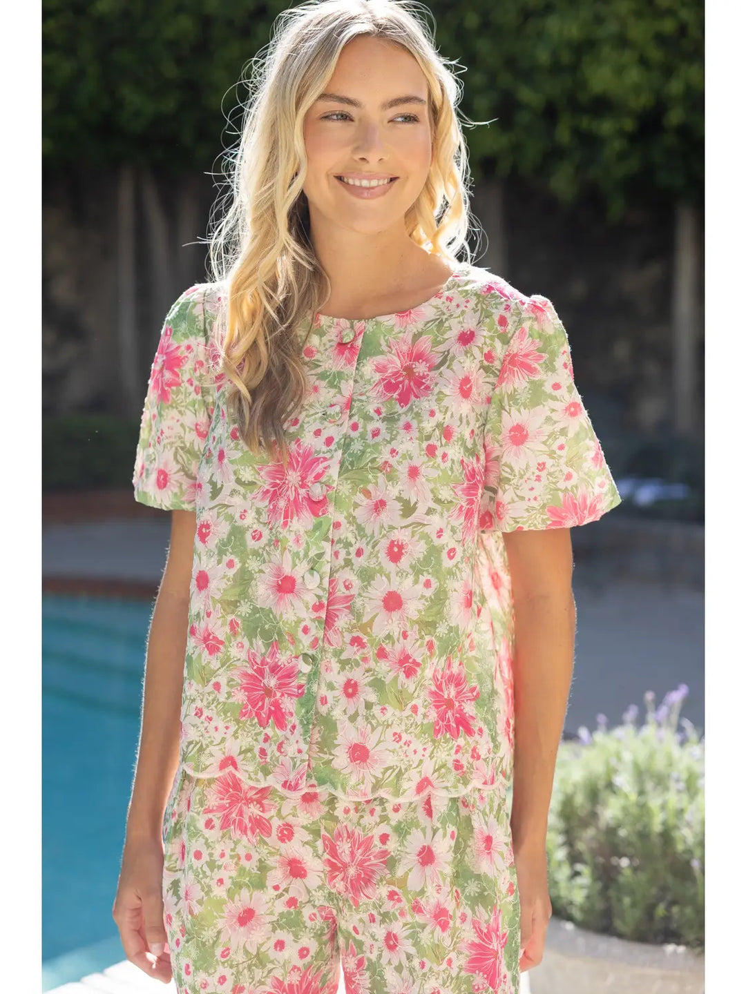 Woman wearing a floral dress standing by a poolside.