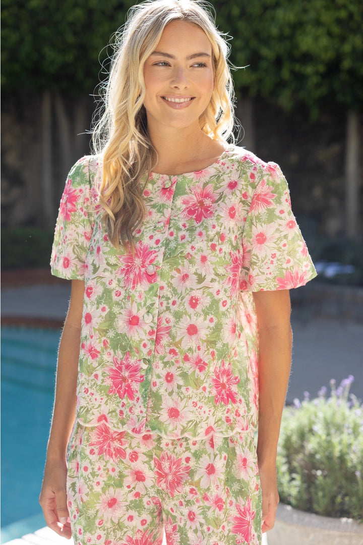 Woman wearing a floral dress standing by a pool with greenery in the background