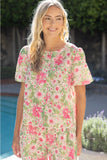 Woman wearing a floral dress standing by a pool with greenery in the background