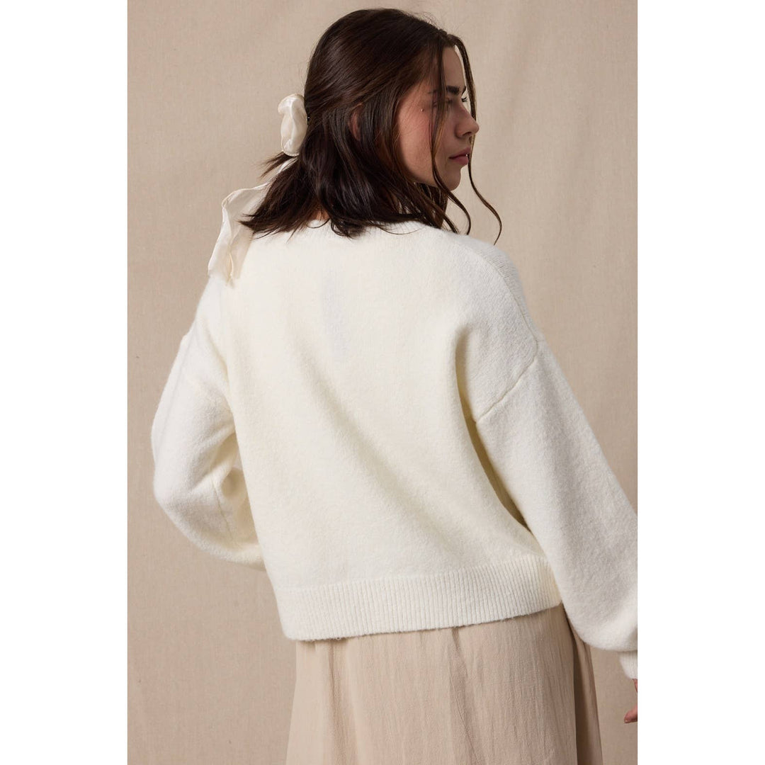Woman wearing a white sweater against a beige background