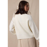 Woman wearing a white sweater against a beige background