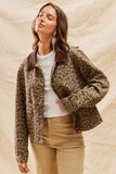 Woman wearing a leopard print jacket over a white shirt and beige pants on a beige background
