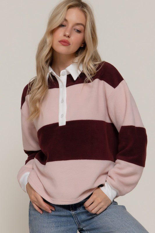 Woman wearing a pink and burgundy striped sweater with a white collar against a beige background