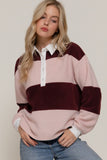 Woman wearing a pink and burgundy striped sweater with a white collar against a beige background