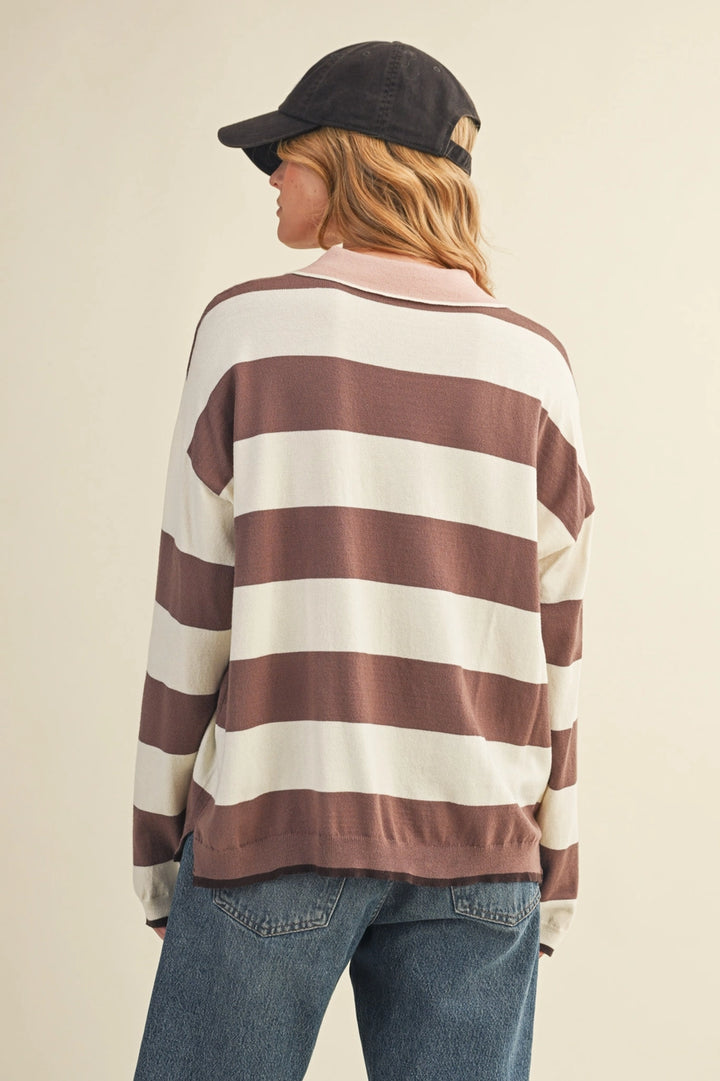 Woman wearing a striped sweater and cap against a plain background.