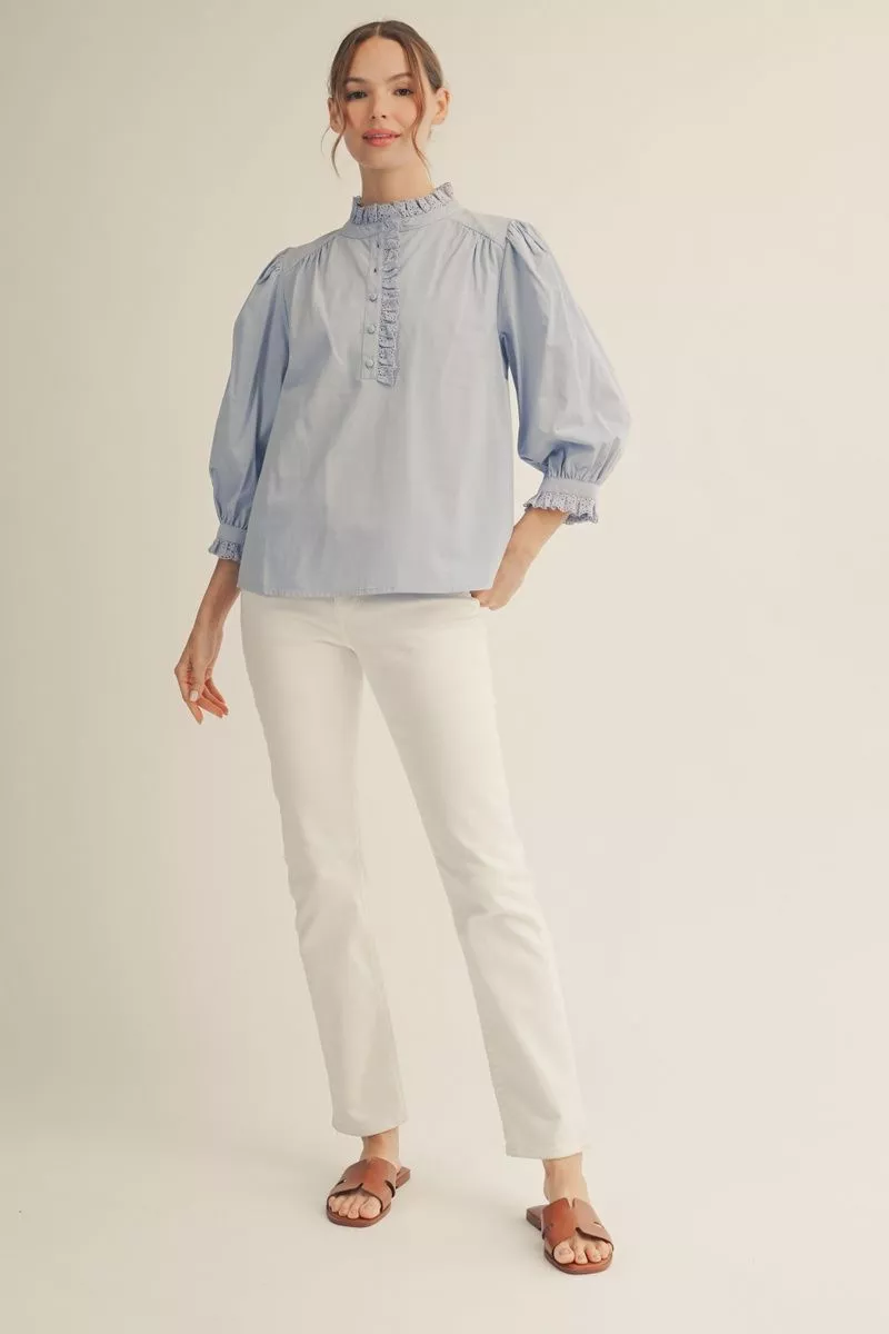 Woman wearing a light blue blouse and white pants on a beige background