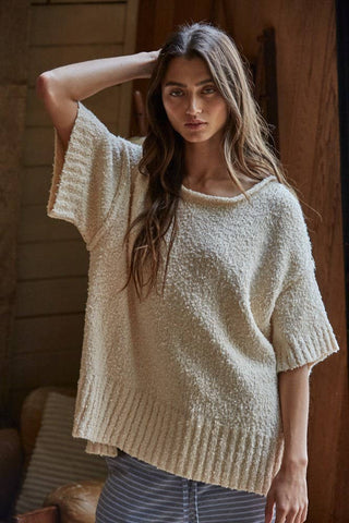 Woman wearing a beige knitted sweater in a warm indoor setting