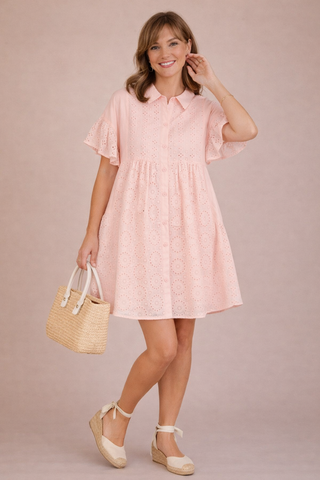 Woman wearing a pink dress holding a straw bag against a beige background