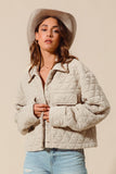 Woman wearing a quilted beige jacket and straw hat on a beige background