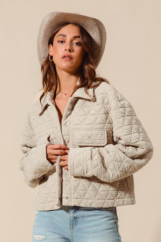 Woman wearing a quilted beige jacket and straw hat on a beige background