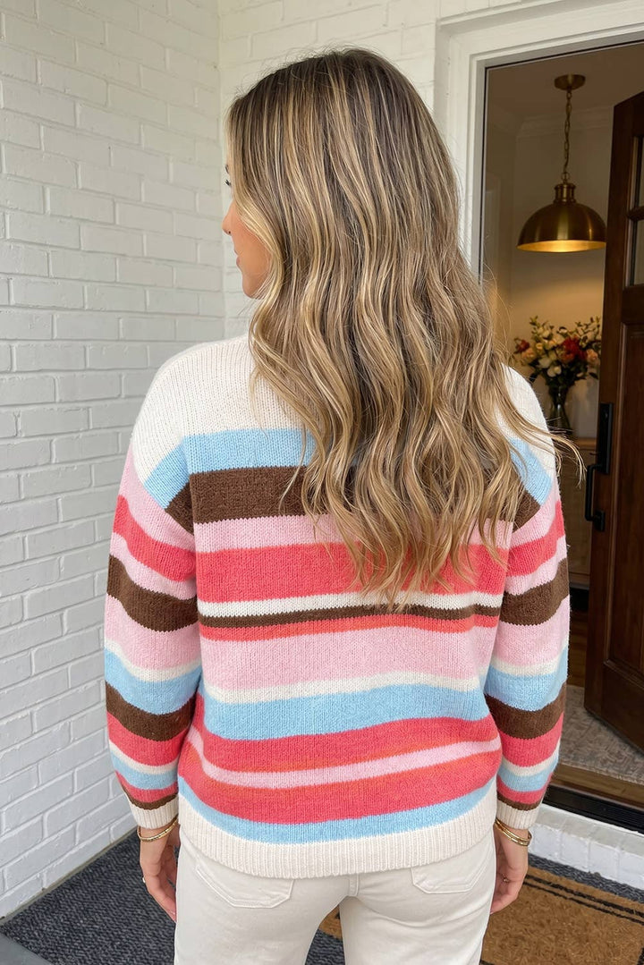 A woman viewed from behind wearing a long-sleeve knit sweater with horizontal stripes in cream, light blue, pink, and brown, paired with off-white pants.