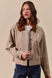 Woman wearing a beige jacket with a brown collar against a beige background