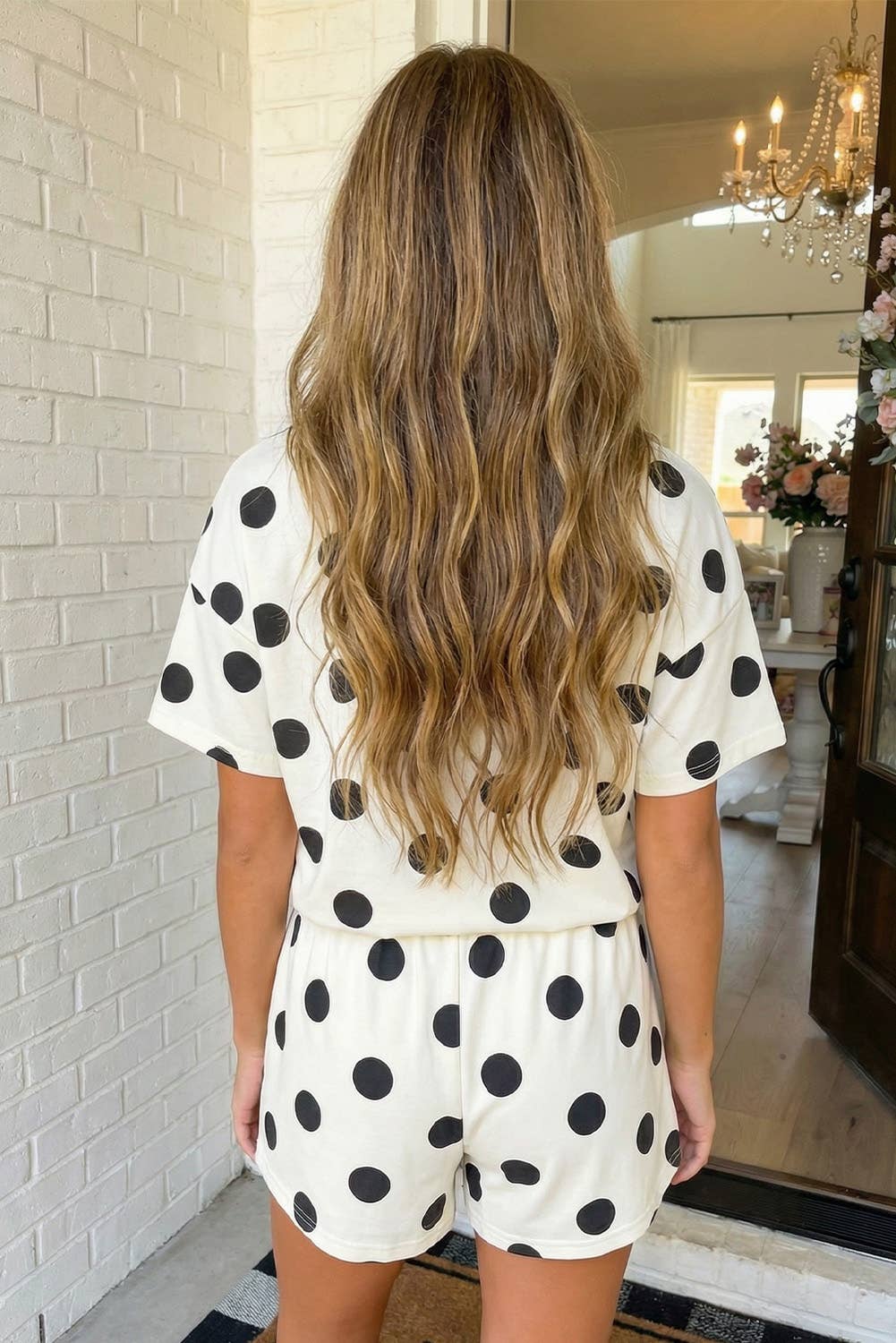 Woman wearing a polka dot outfit standing in a home interior.