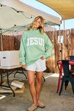 Person wearing a light green 'JESUS' sweatshirt in an outdoor setting.