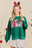 Woman wearing a green sweater with plaid design and red headband in festive setting