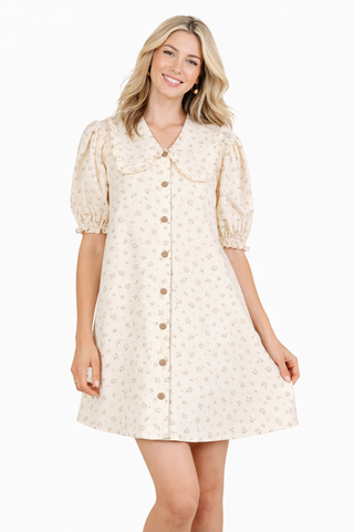 Woman wearing a cream-colored dress with puff sleeves on a white background