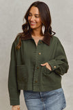 Woman wearing a green jacket with a brown collar against a gray background