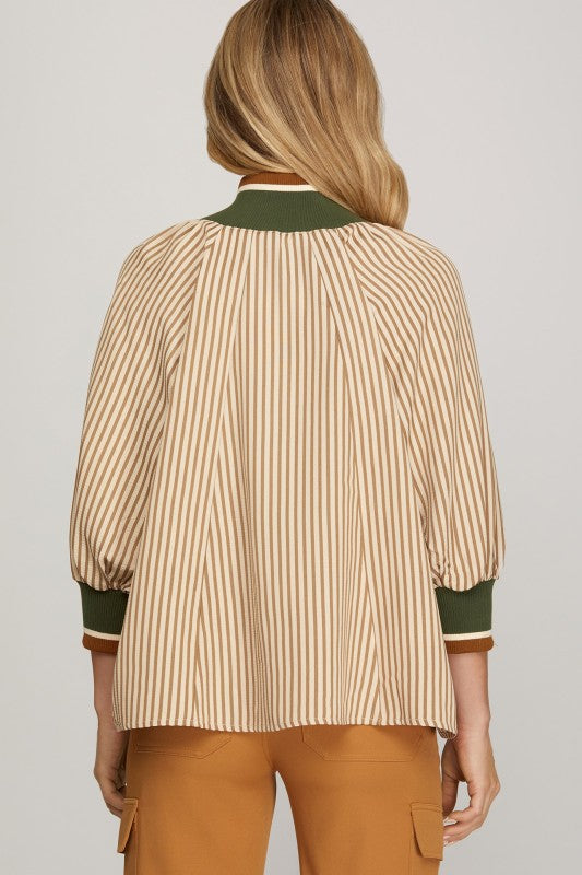 Woman wearing a beige and green striped shirt with a plain background