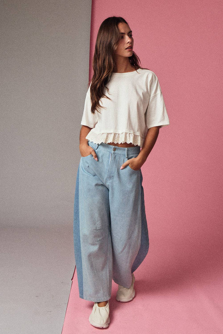 Woman wearing a white top and light blue jeans against a pink background