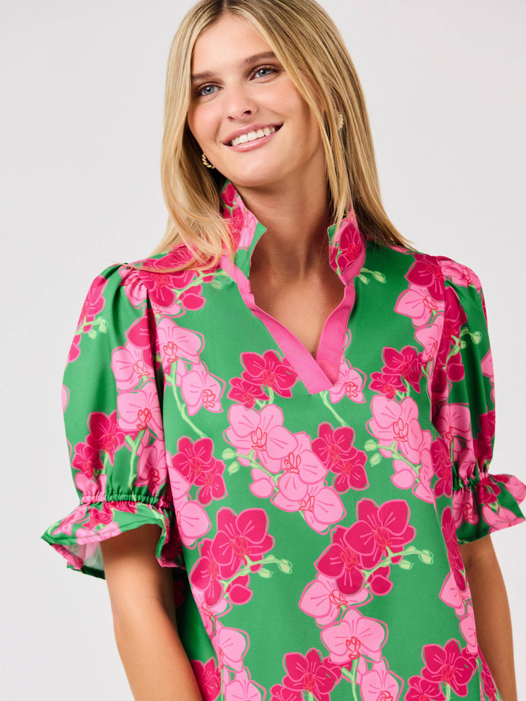 Woman wearing a green floral dress with pink flowers on a white background