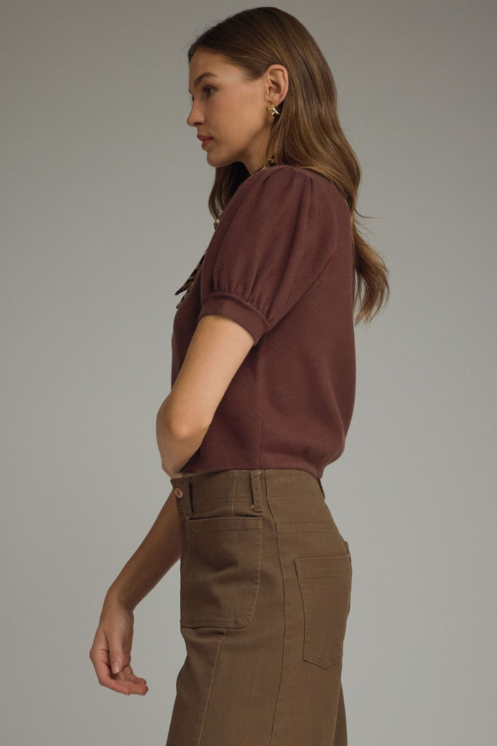 Woman wearing a brown top and pants against a gray background