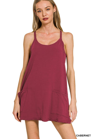 Woman wearing a maroon sleeveless dress with pockets on a white background