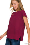 Woman wearing a maroon sleeveless knitted top on a white background