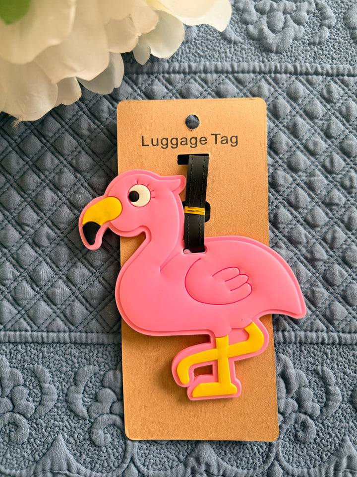 Pink flamingo-shaped luggage tag on a textured gray surface