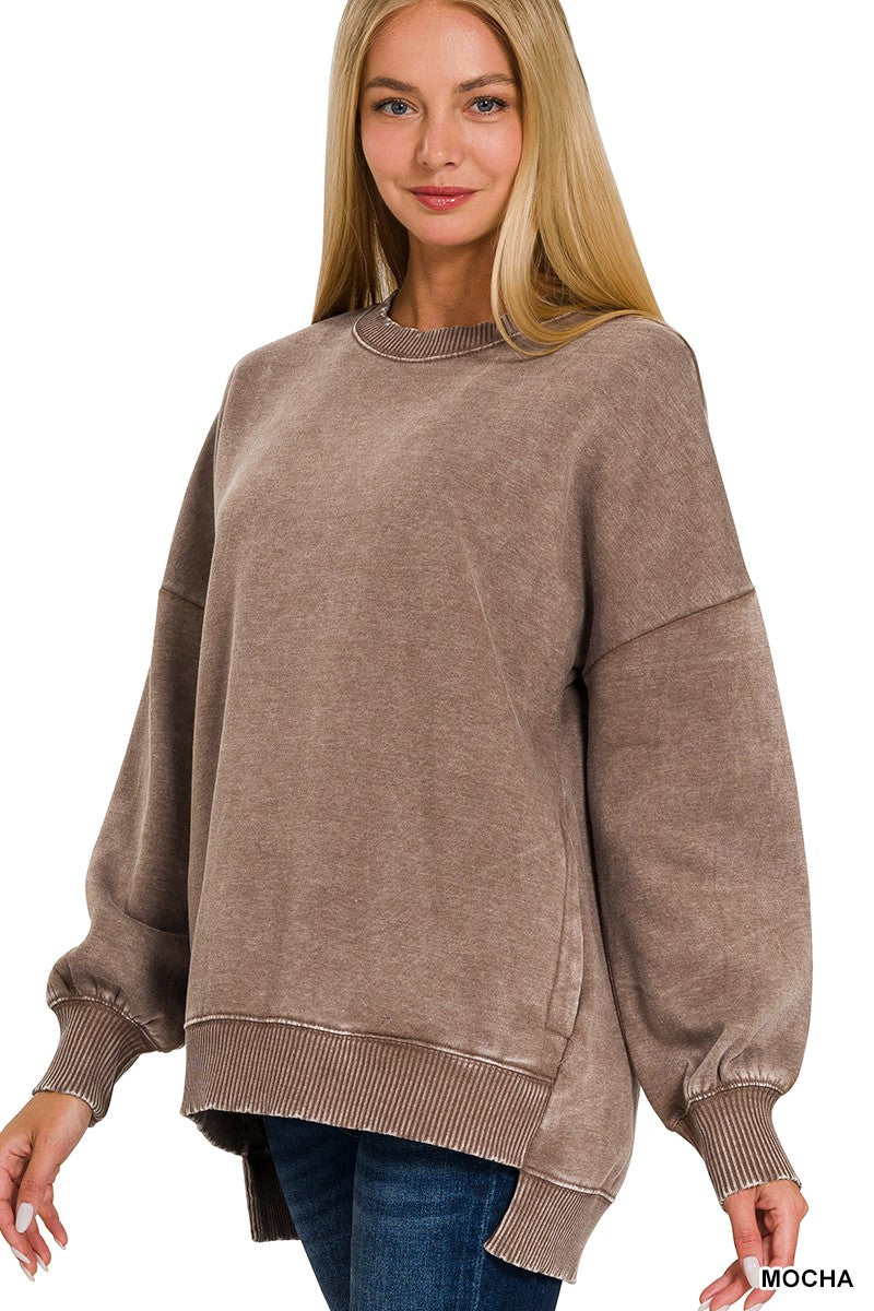 A woman wearing an oversized, long-sleeve crewneck sweatshirt in a washed mocha brown color, paired with blue jeans, against a plain white background.