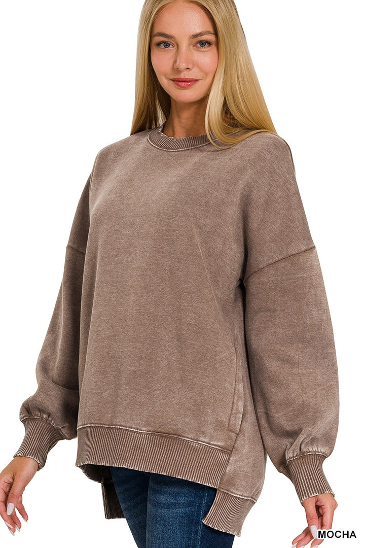 A woman wearing an oversized, long-sleeve crewneck sweatshirt in a washed mocha brown color, paired with blue jeans, against a plain white background.