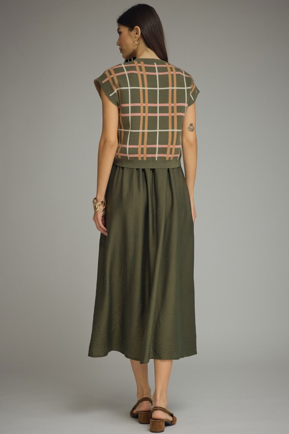 Woman wearing a green dress with a plaid pattern on a gray background