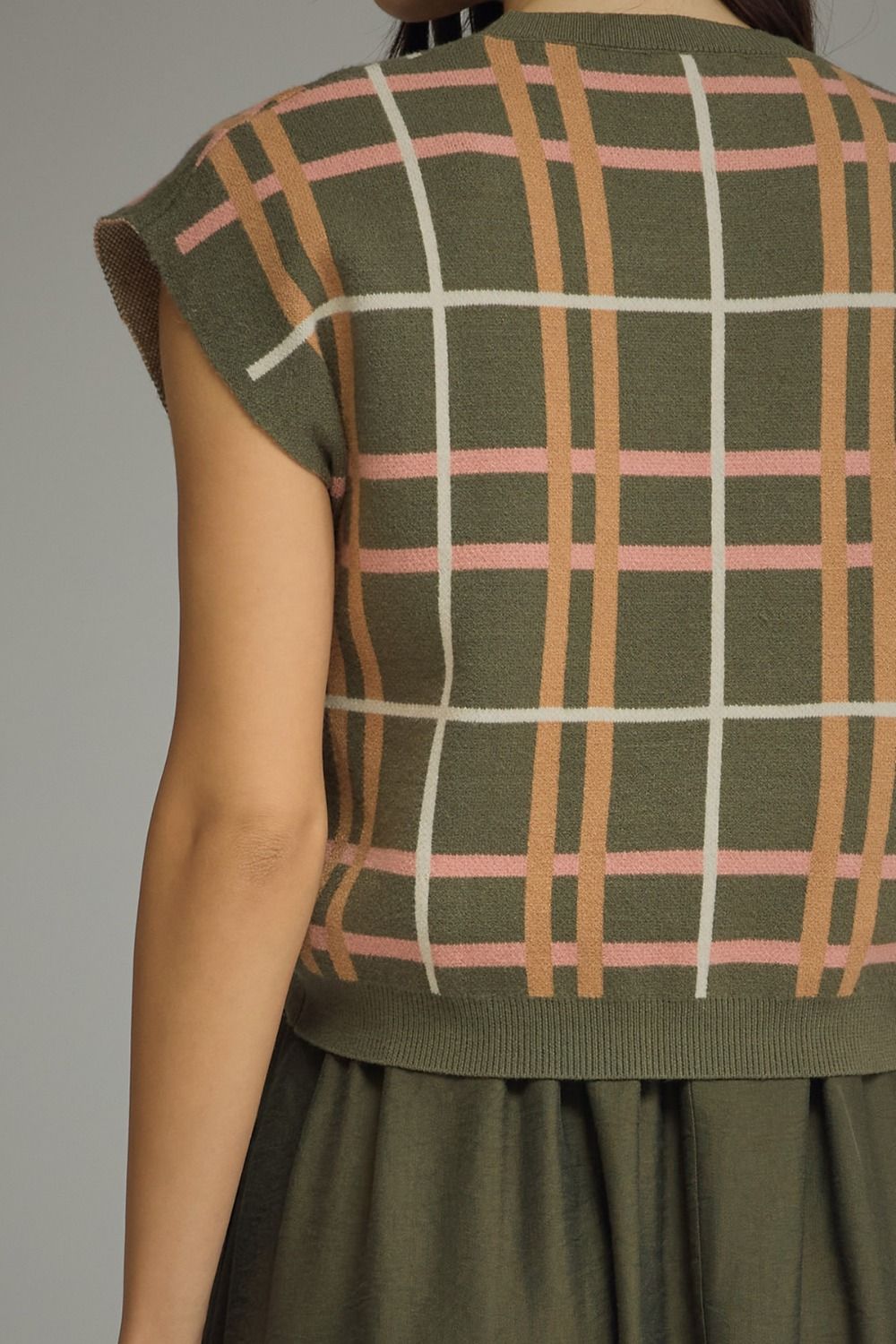 Green plaid sleeveless top worn by a person on a gray background