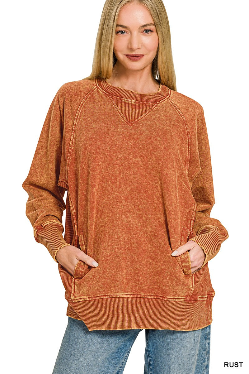 A person wearing a loose, long-sleeve rust-orange top against a plain light background.