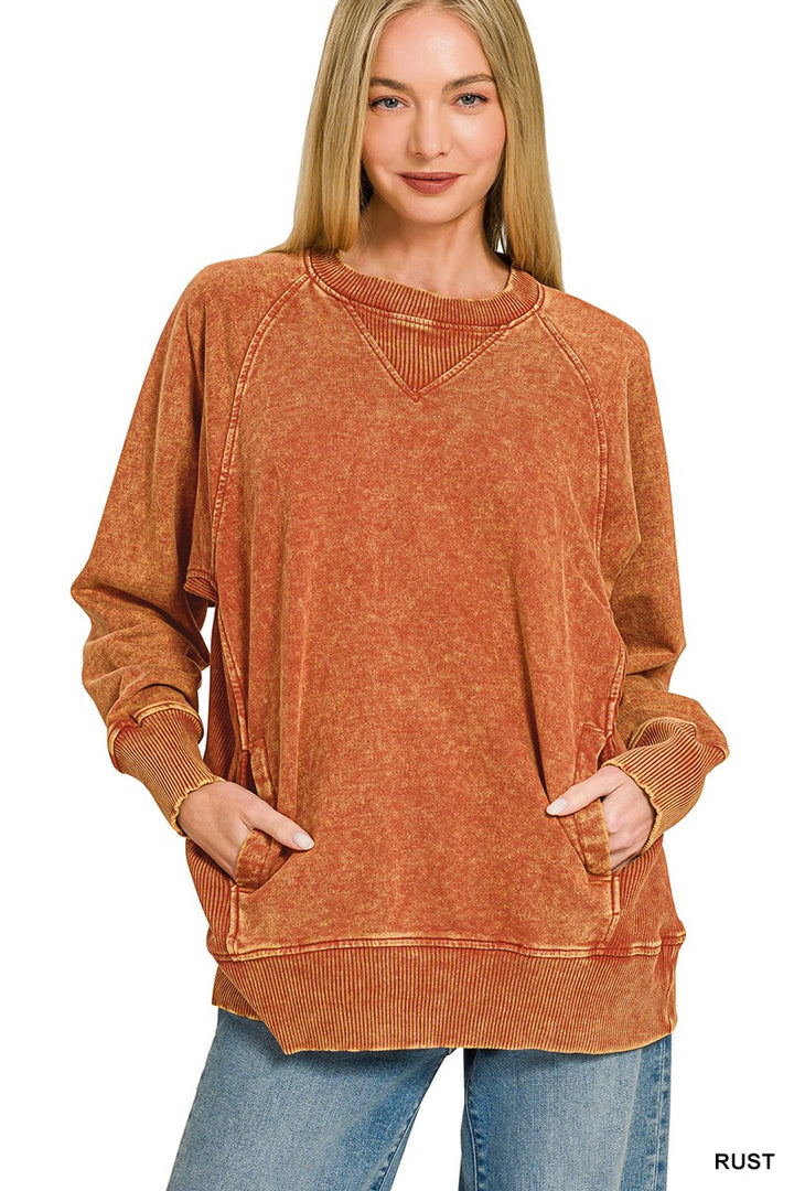 A person wearing a loose, long-sleeve rust-orange top against a plain light background.